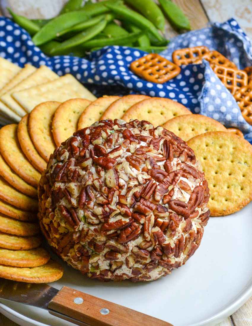 savory pecan crusted cheeseball on a white plate surrounded by crackers