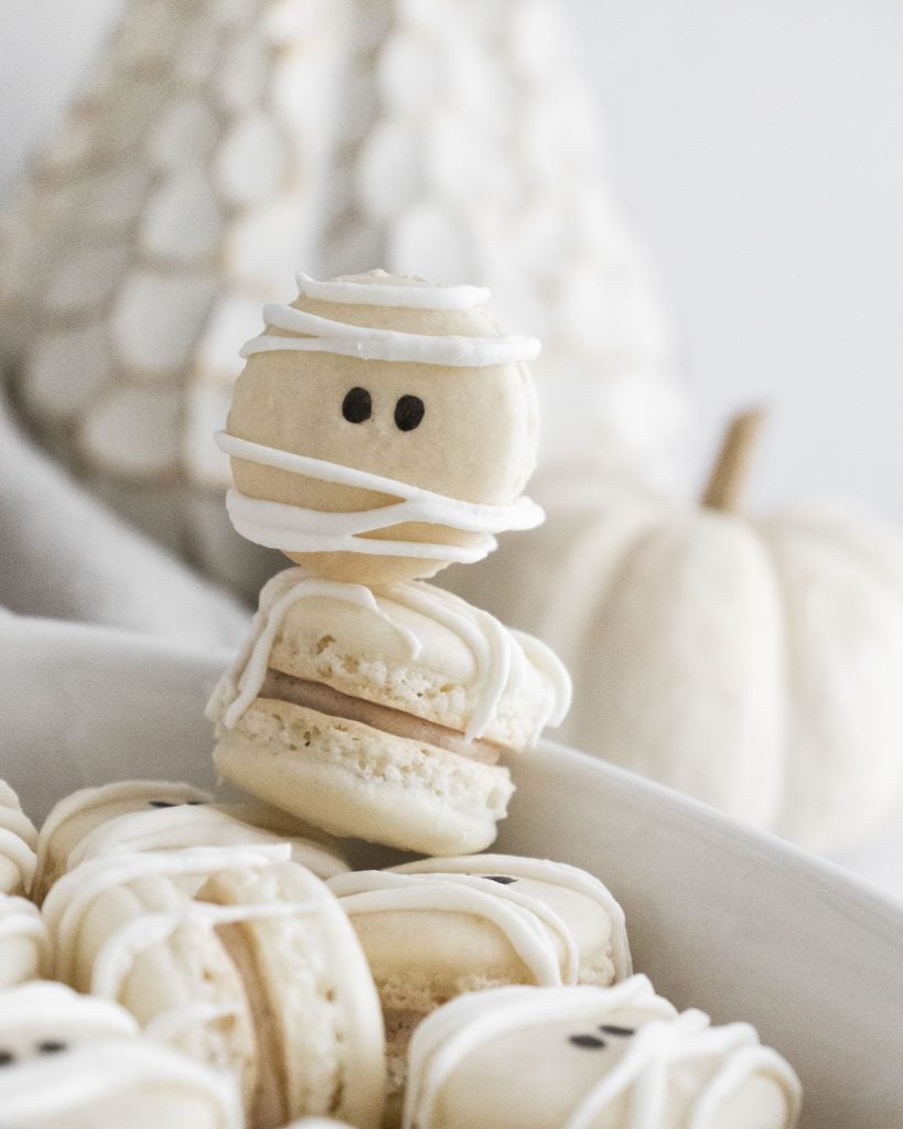 mummy macarons stacked in a white serving dish