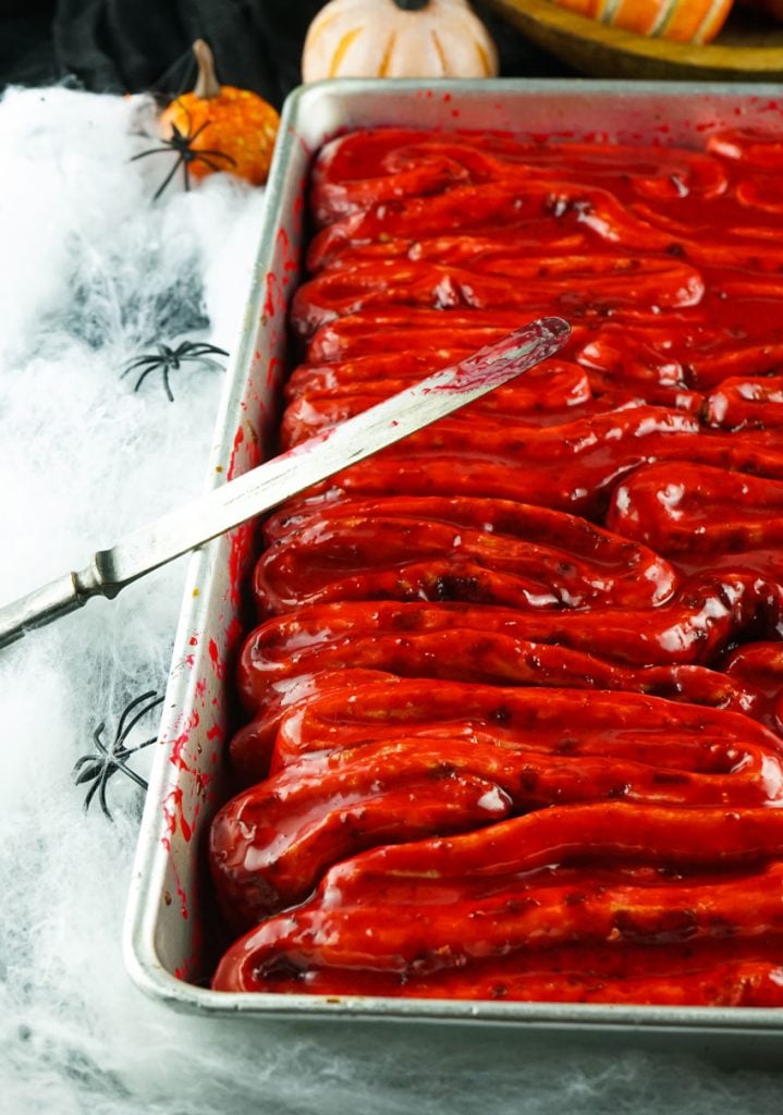 blood & guts cinnamon rolls in a silver baking dish with a bloody butter knife resting on the side