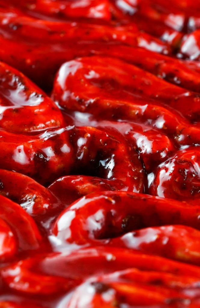 a close up showing blood red gooey coated baked cinnamon rolls unwound and folded like guts