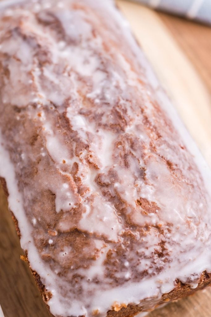 a glazed apple cider pound cake on a wooden cutting board
