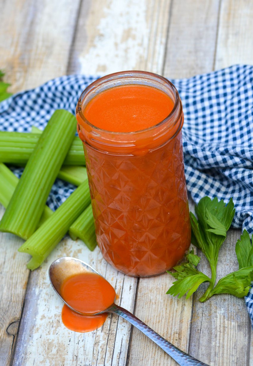 homemade buffalo sauce in a glass mason jar and shown in a silver spoon on the side