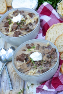 beef stroganoff soup served in two gray bowls with dollops of fresh sour cream