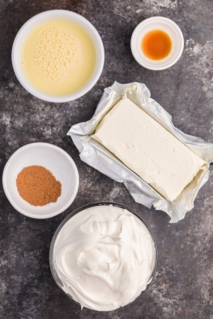 an overhead image showing the ingredients needed to make eggnog dip laid out on a black counter top
