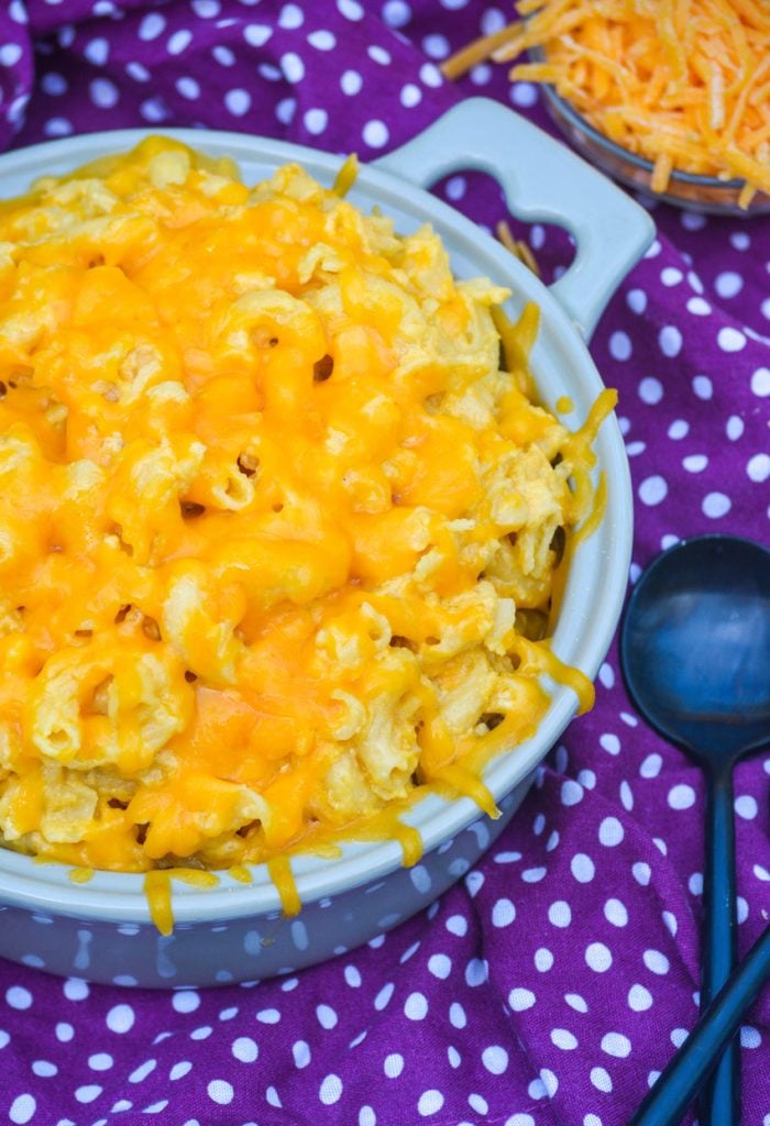 slow cooker macaroni & cheese in a gray bowl with a melted cheese topping