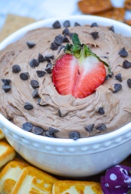 brownie batter dip in a white bowl topped with chocolate chips & a sliced strawberry stuck in the middle