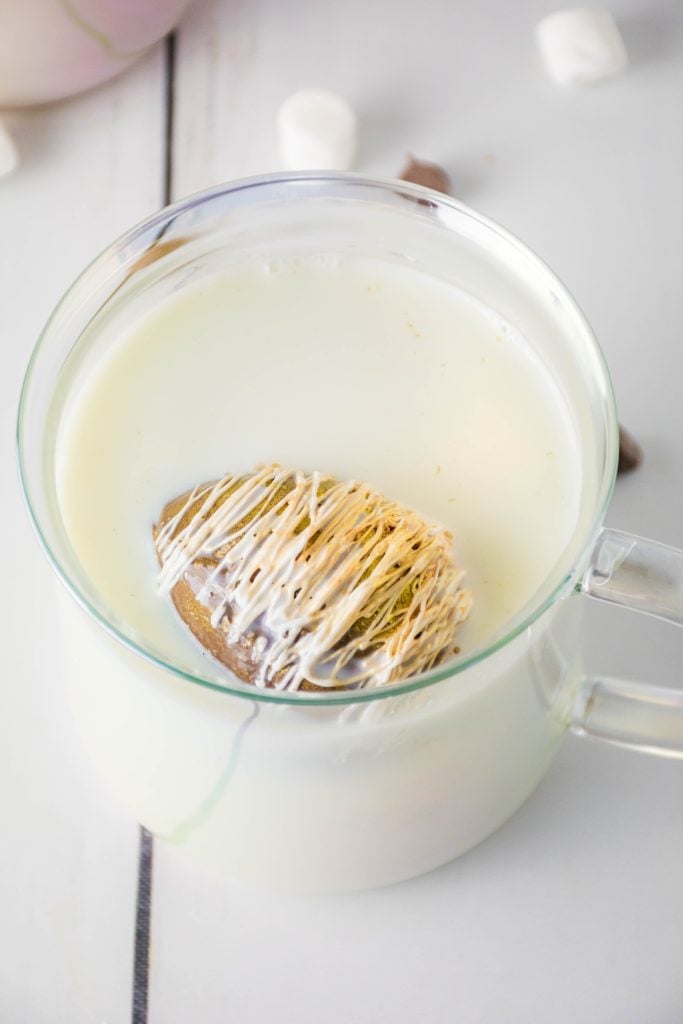 eggnog hot cocoa bombs floating in a glass mug filled with milk