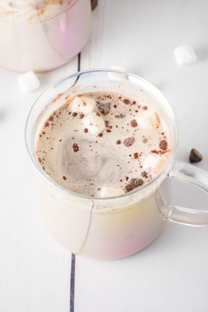 marshmallows floating on top of hot cocoa in a glass mug