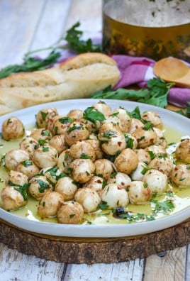 marinated mozzarella balls topped with fresh herbs on a gray plate