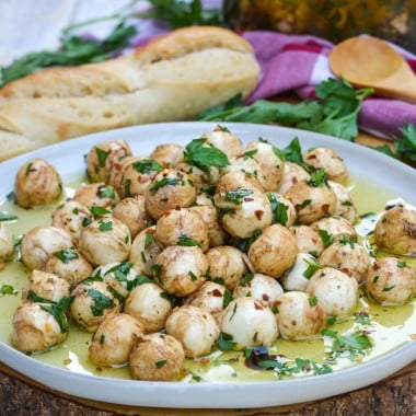 marinated mozzarella balls topped with fresh herbs on a gray plate