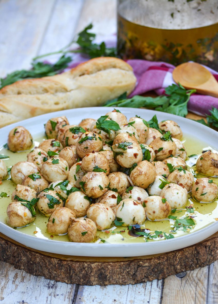 marinated mozzarella balls topped with fresh herbs on a gray plate