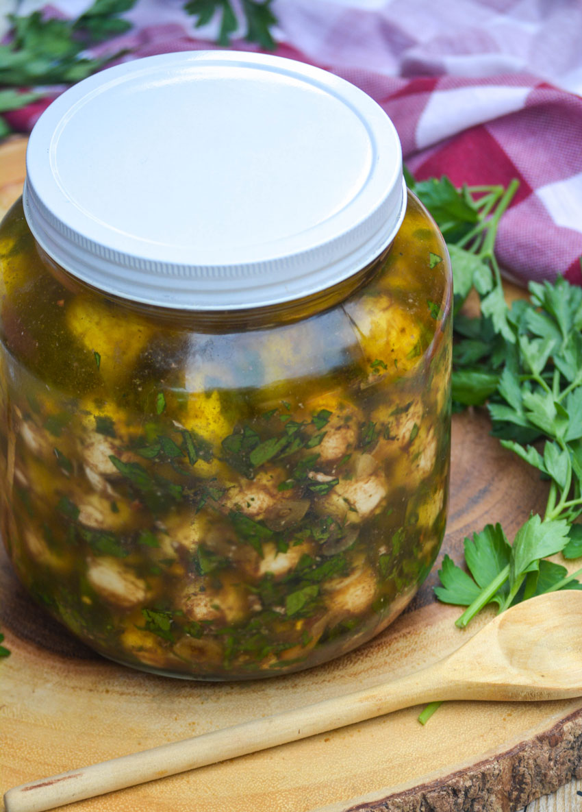 marinated mozzarella balls with herbs in olive oil in a large glass jar