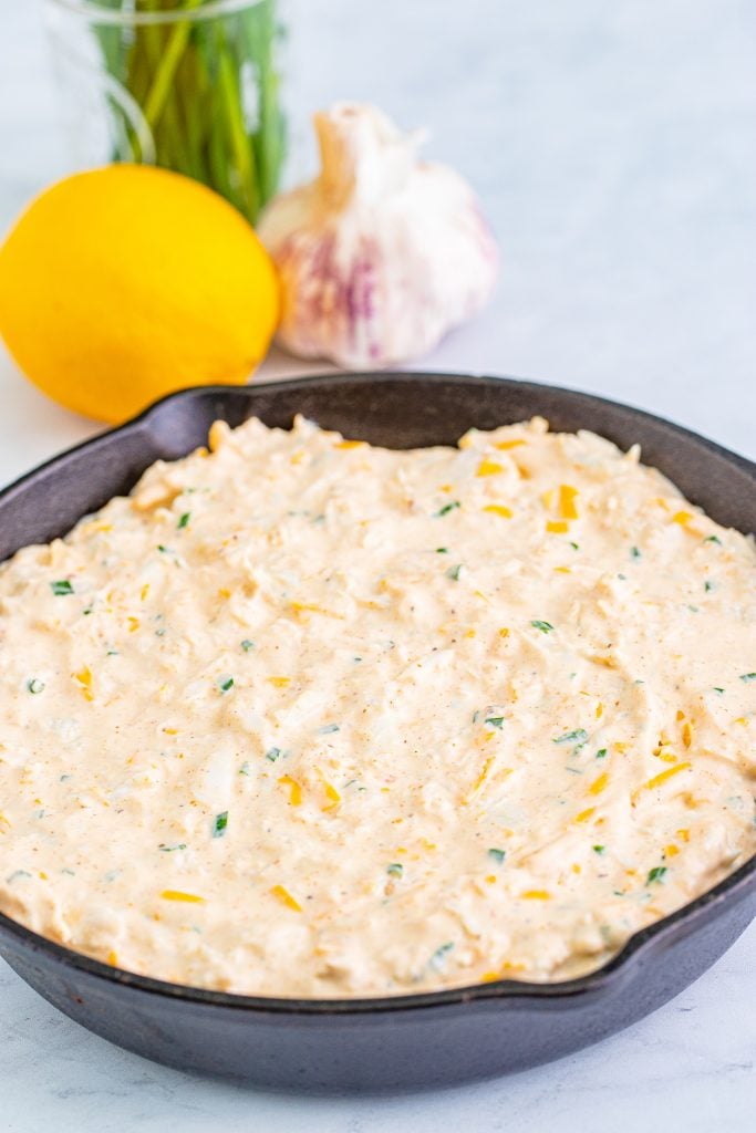 crab dip spread out in a black cast iron skillet