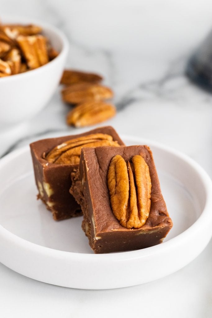 squares of secret ingredient fudge with nuts stacked on a white plate