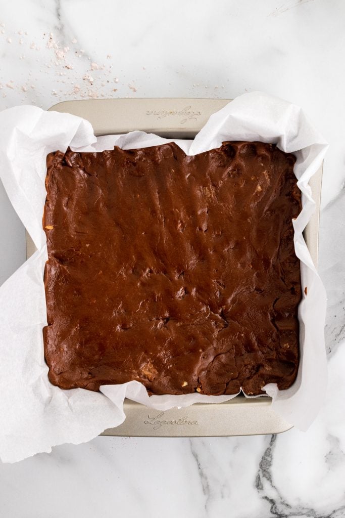 chocolate cheese fudge spread in a parchment paper lined square baking dish
