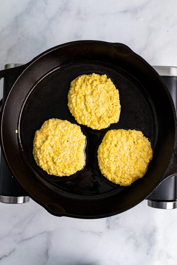 hot water cornbread batter in three cakes in a cast iron skillet