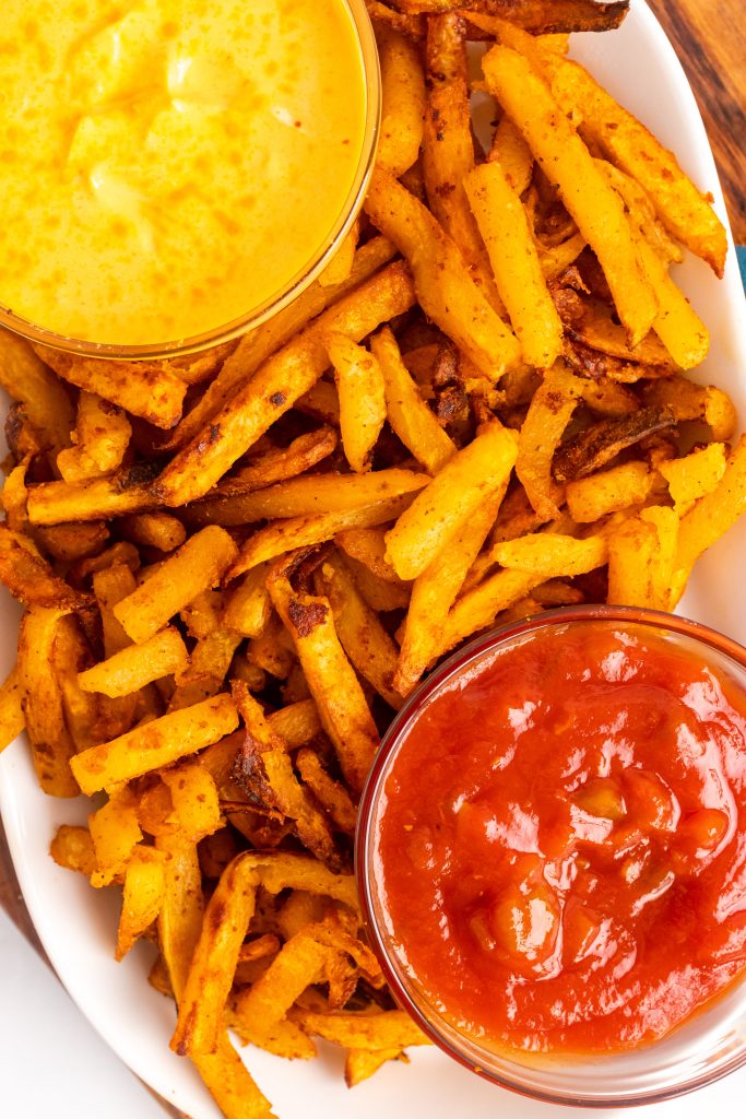 copycat nacho fries on a white platter with small bowls filled with sauces