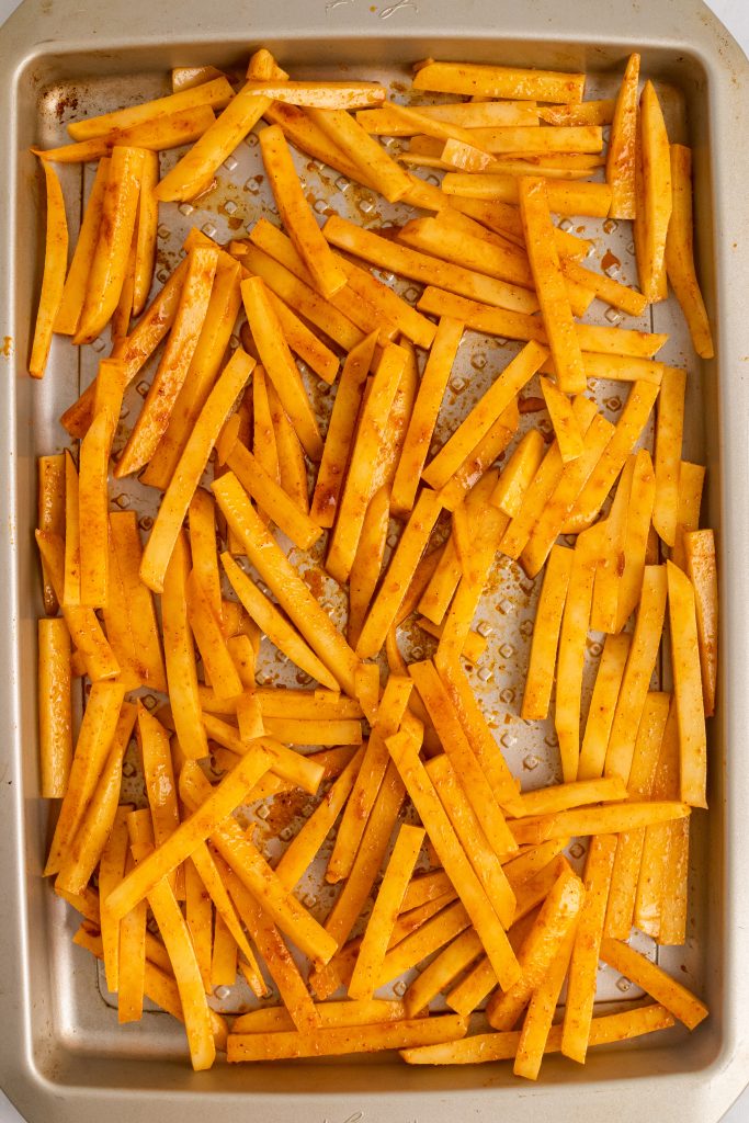 seasoned cut fresh fries on a metal baking sheet