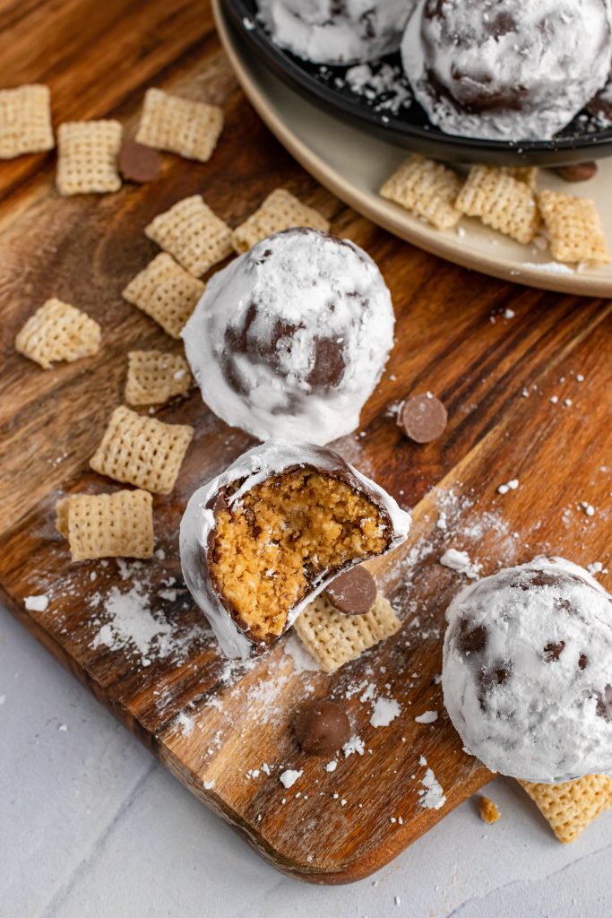 puppy chow truffles on a wooden cutting board