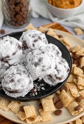a black plate with a pile of powdered sugar covered puppy chow truffles on it