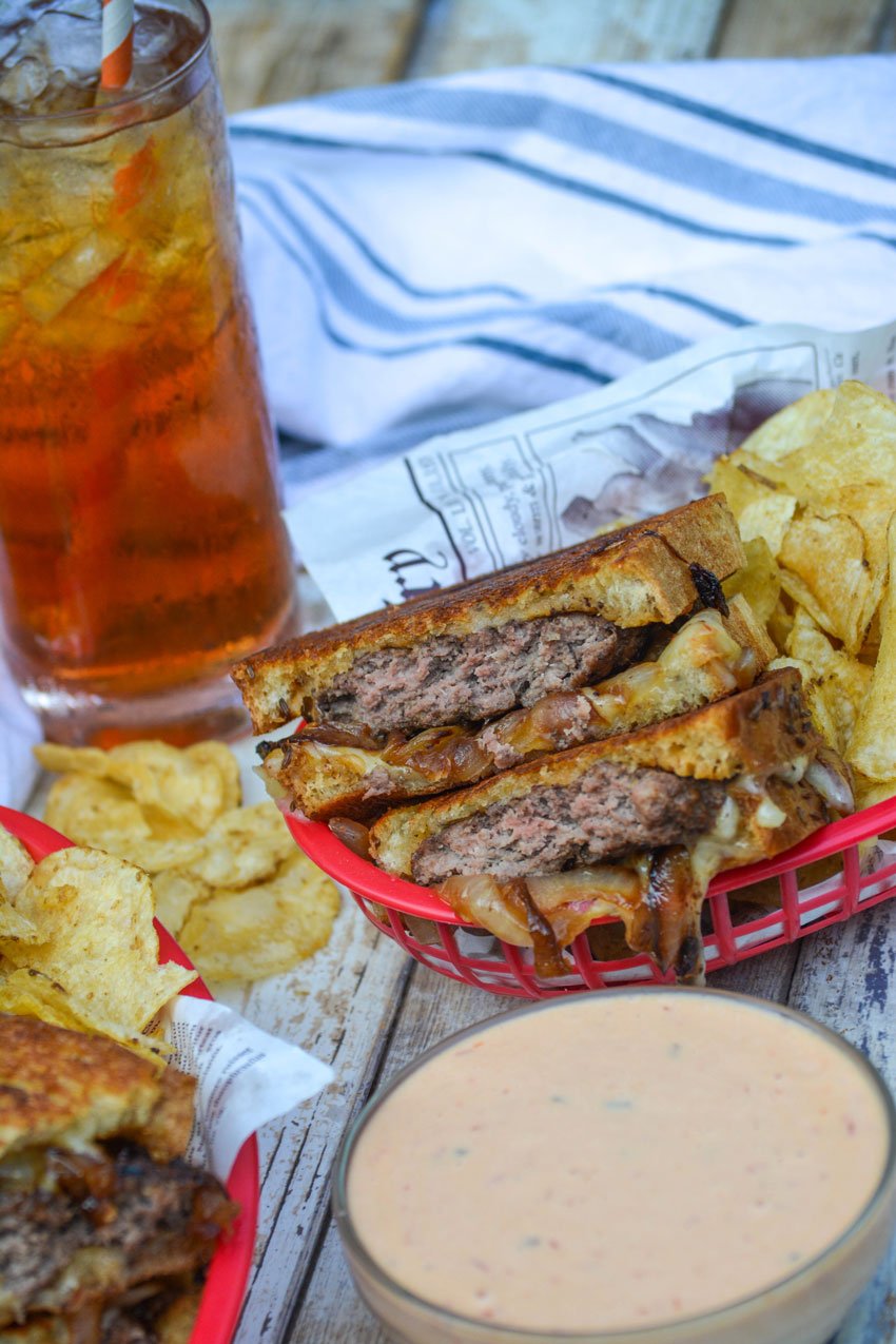 classic patty melts served with chips in paper lined red plastic fast food baskets