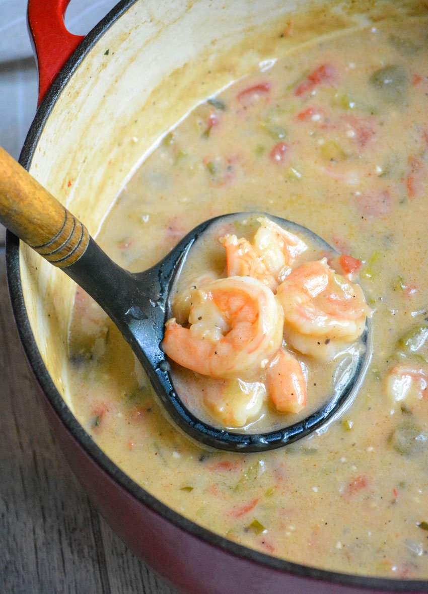 shrimp etouffee in a black ladle held above a Dutch oven