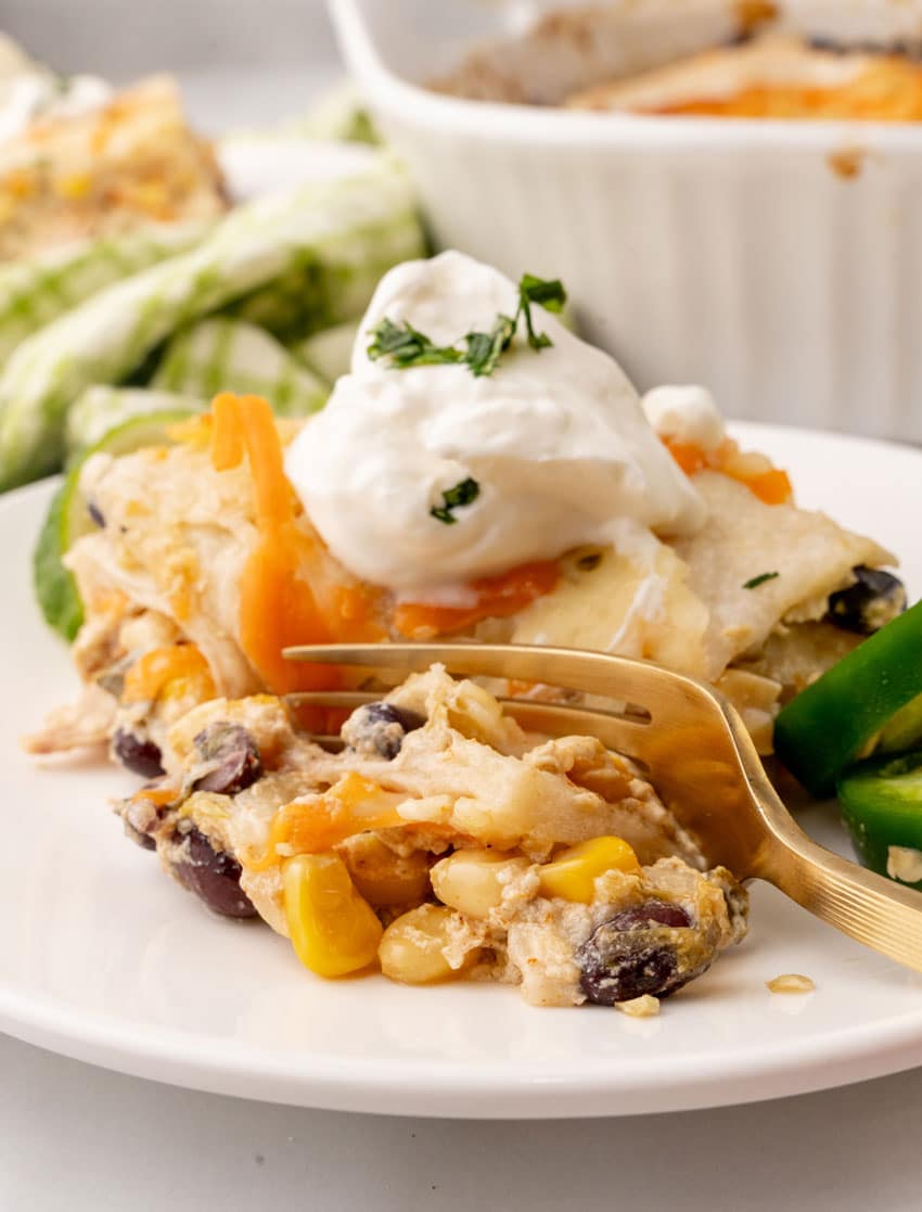 a slice of Mexican lasagna topped with a dollop of sour cream on a white plate