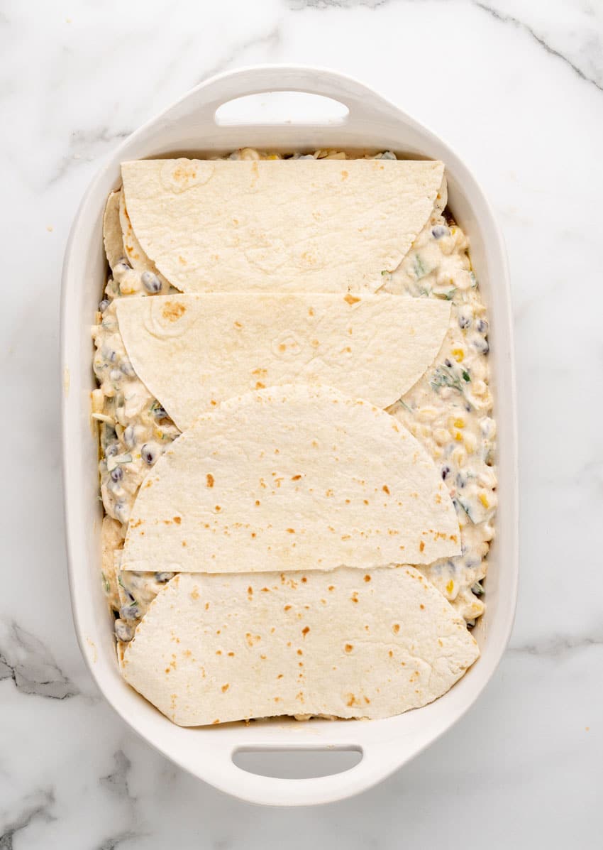 a layered tex mex lasagna in a white casserole dish