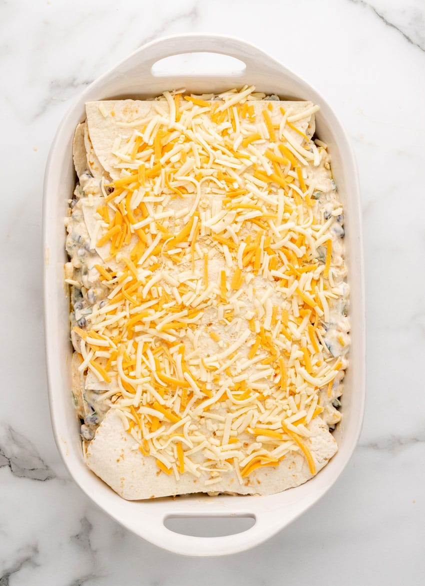 a layered tex mex lasagna in a white casserole dish