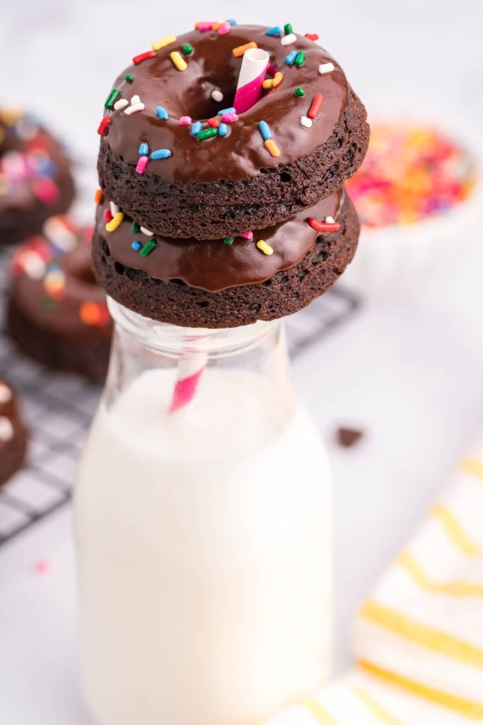 double chocolate donuts resting on the rim of a glass jar filled with milk