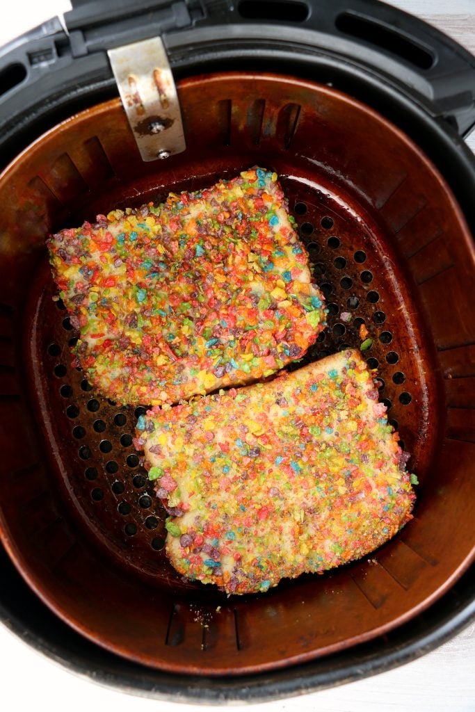 two slices of air fryer fruity pebbles french toast in the basket of an air fryer