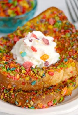 two slices of fruity pebble crusted french toast stacked together on a white plate