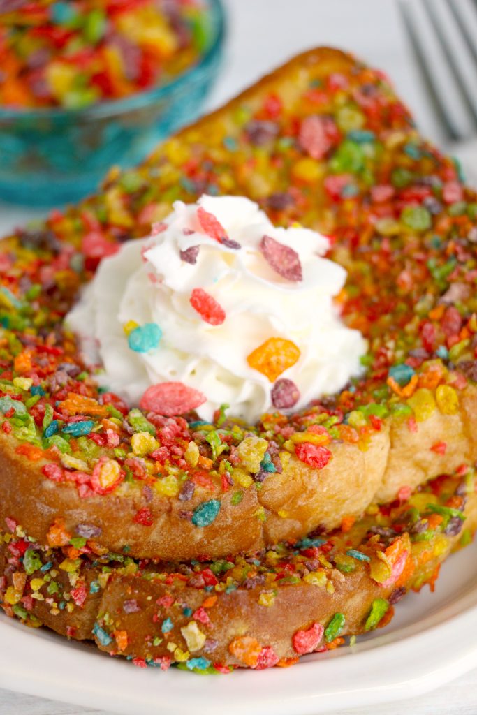 two sliced of fruity pebble crusted french toast stacked together on a white plate