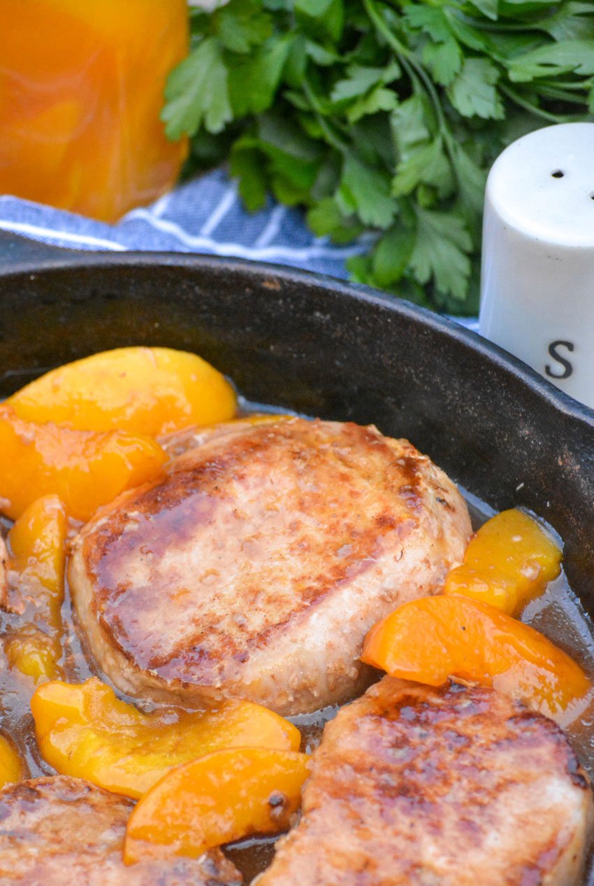 a close up of the meat and fruit in this peaches and pork chop skillet