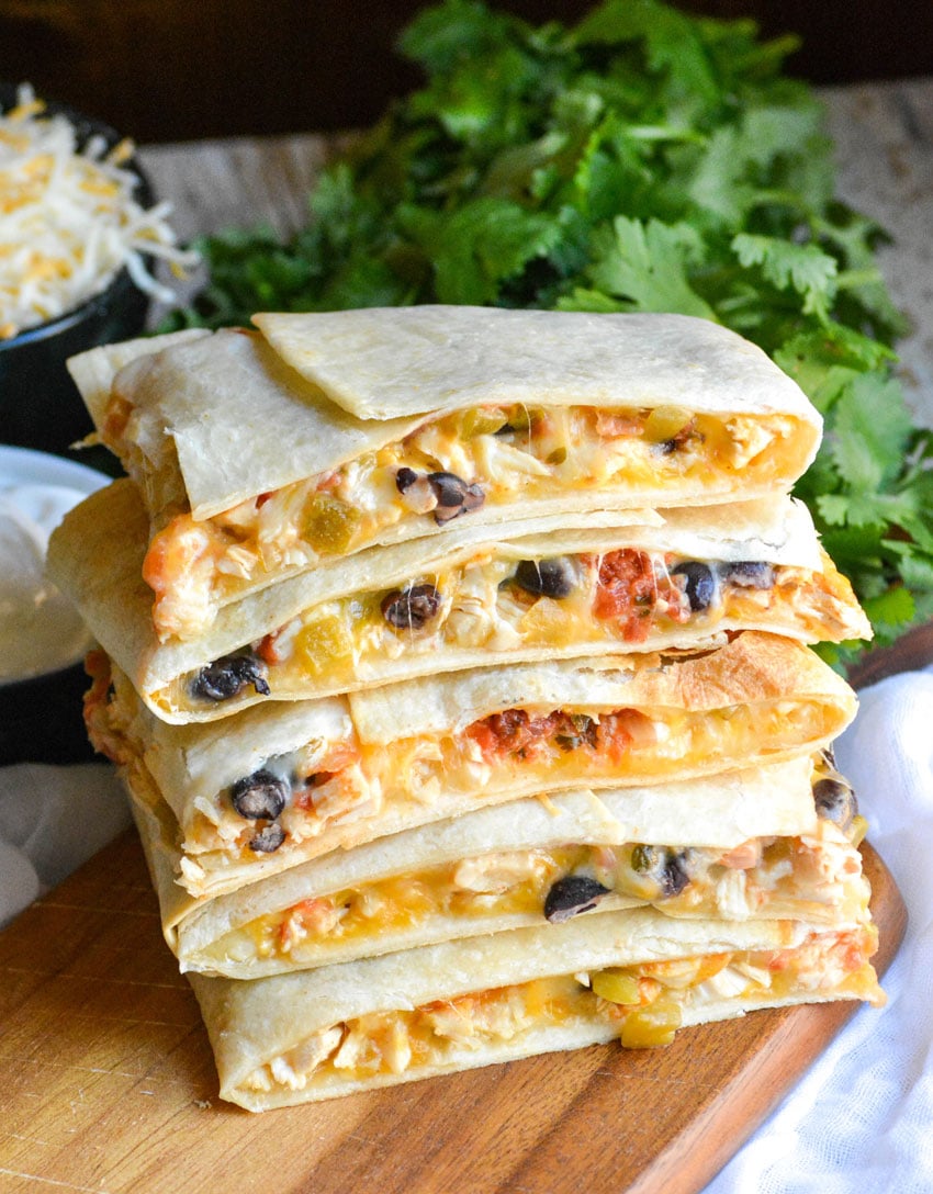 a stack of sheet pan chicken quesadillas on a wooden cutting board
