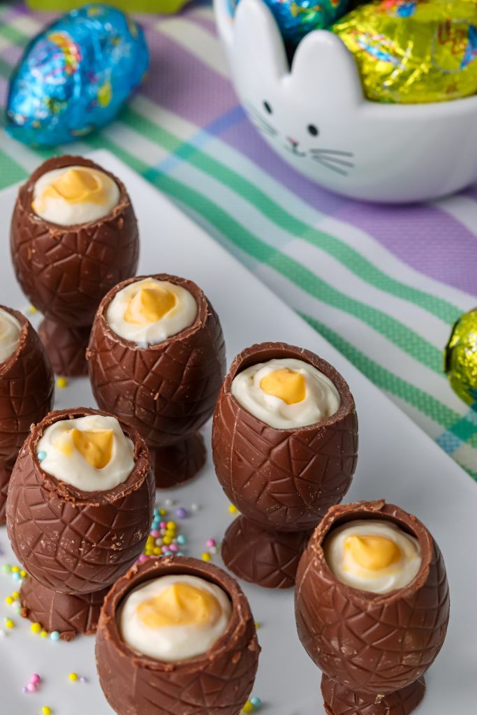 cheesecake stuffed chocolate eggs arranged in two rows on a white platter