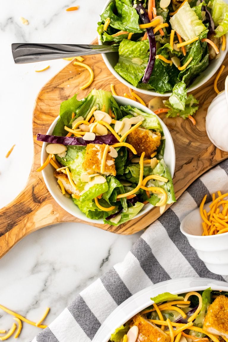 copycat Applebee's oriental chicken salad on two white plates on a wooden cutting board