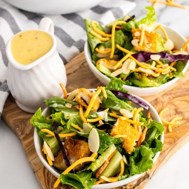 oriental chicken salad on two white plates on a wooden cutting board