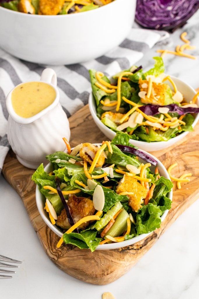 oriental chicken salad on two white plates on a wooden cutting board