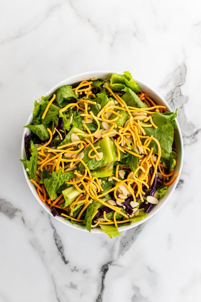 tossed salad topped with crispy chow mein noodles in a white bowl