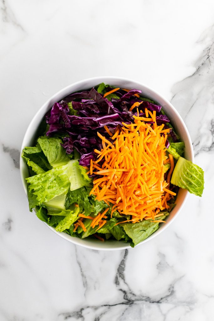 lettuce leaves, shredded purple cabbage, and carrot sticks in a white bowl