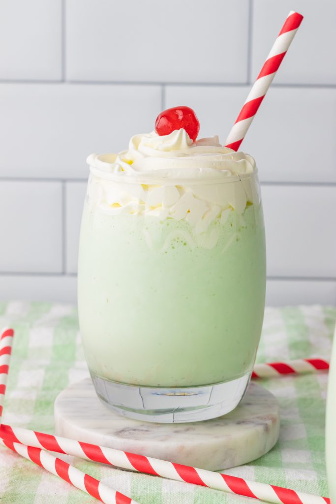 copycat shamrock shakes in glass jars topped with whipped cream and a maraschino cherry on top