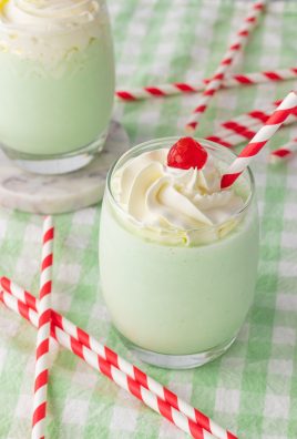 copycat shamrock shakes in glass jars topped with whipped cream and a maraschino cherry on top