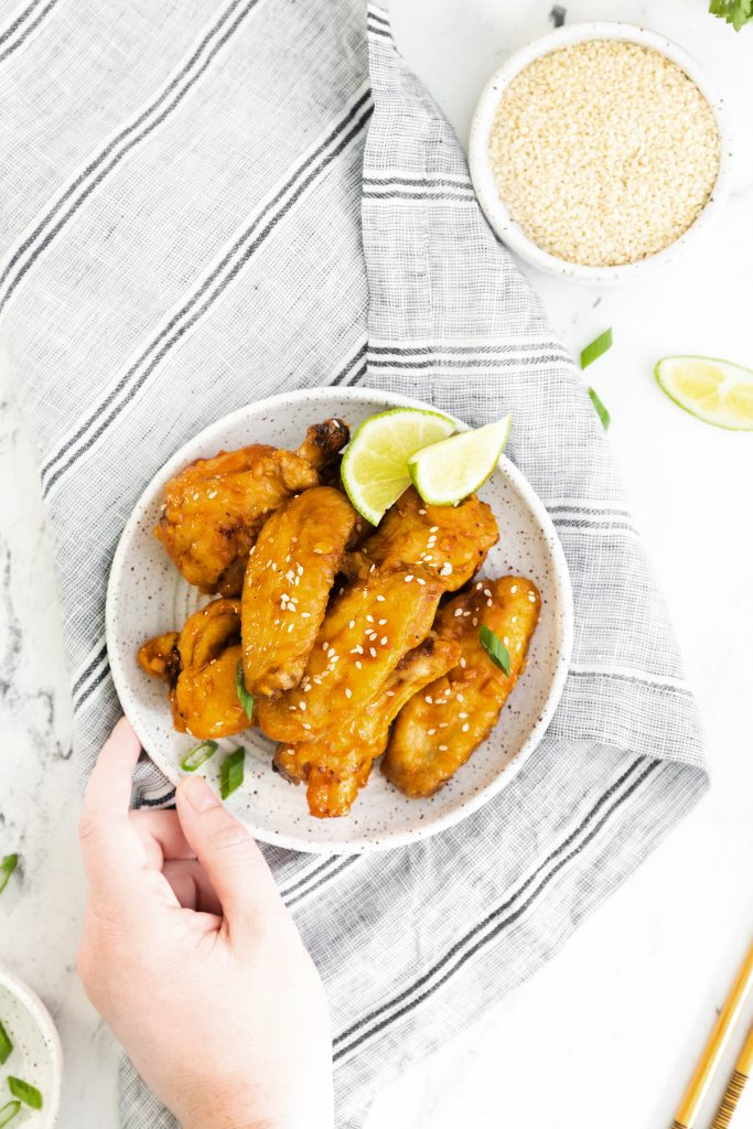 air fryer asian sticky wings on a white plate with lime wedges