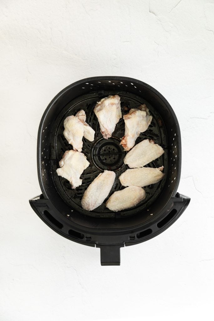 uncooked chicken wings in the basket of an air fryer