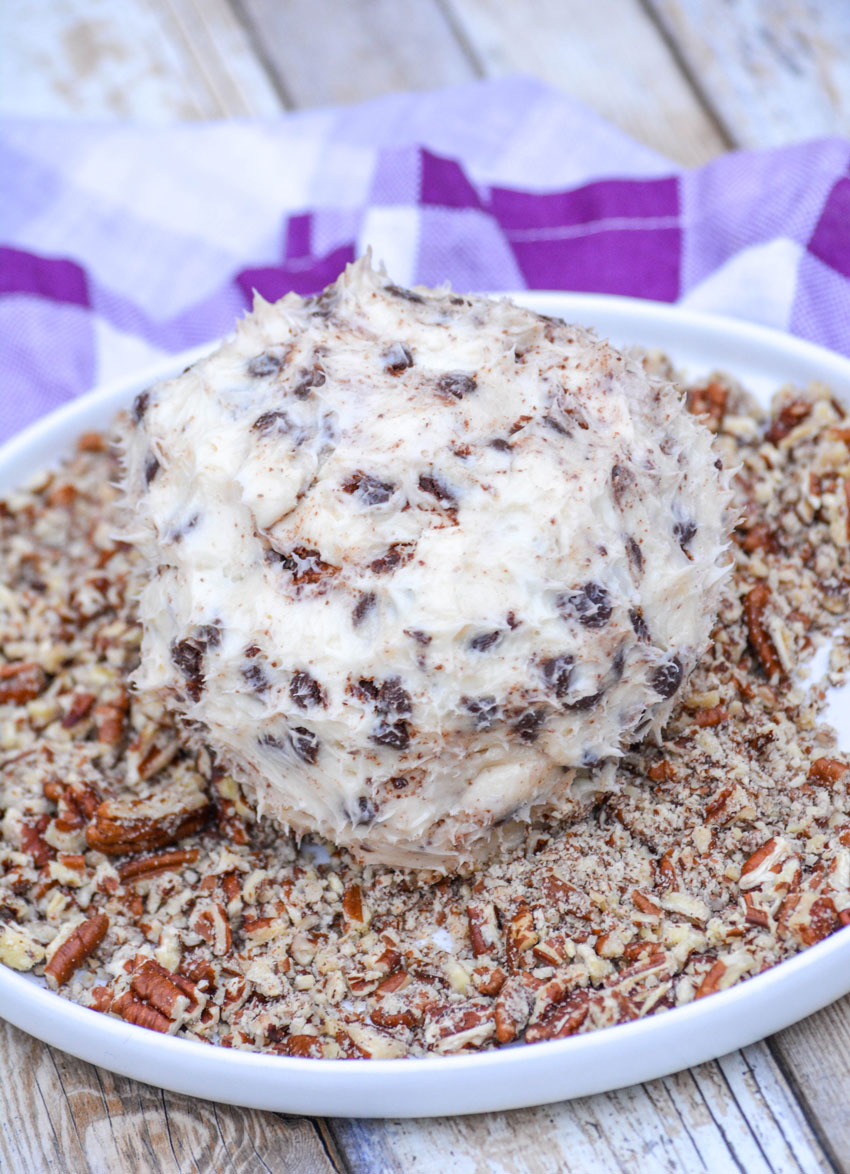 the best dessert cheeseball on a plate of crushed pecans