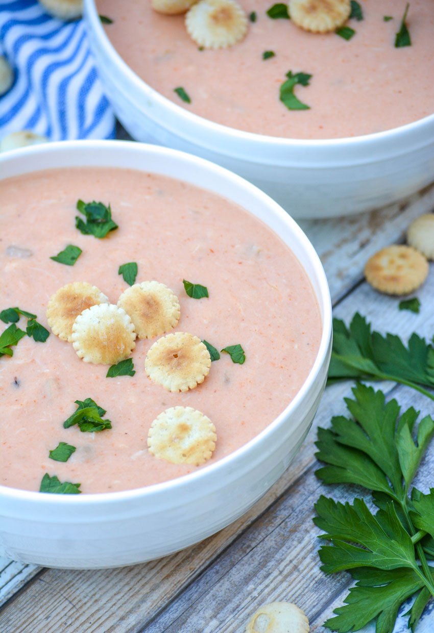 easy crab bisque in two white bowls topped with fresh herbs and oyster crackers