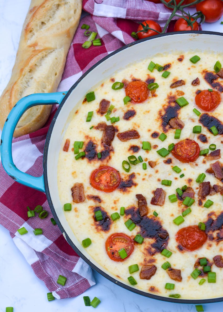 kentucky hot brown dip in an enameled cast iron skillet with a fresh baguette on the side