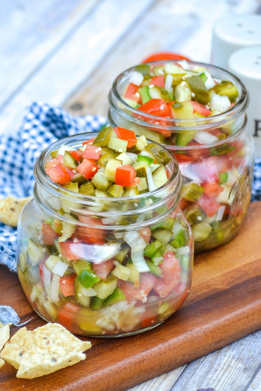 fresh pickle de gallo in two small glass mason jars on a wooden cutting board