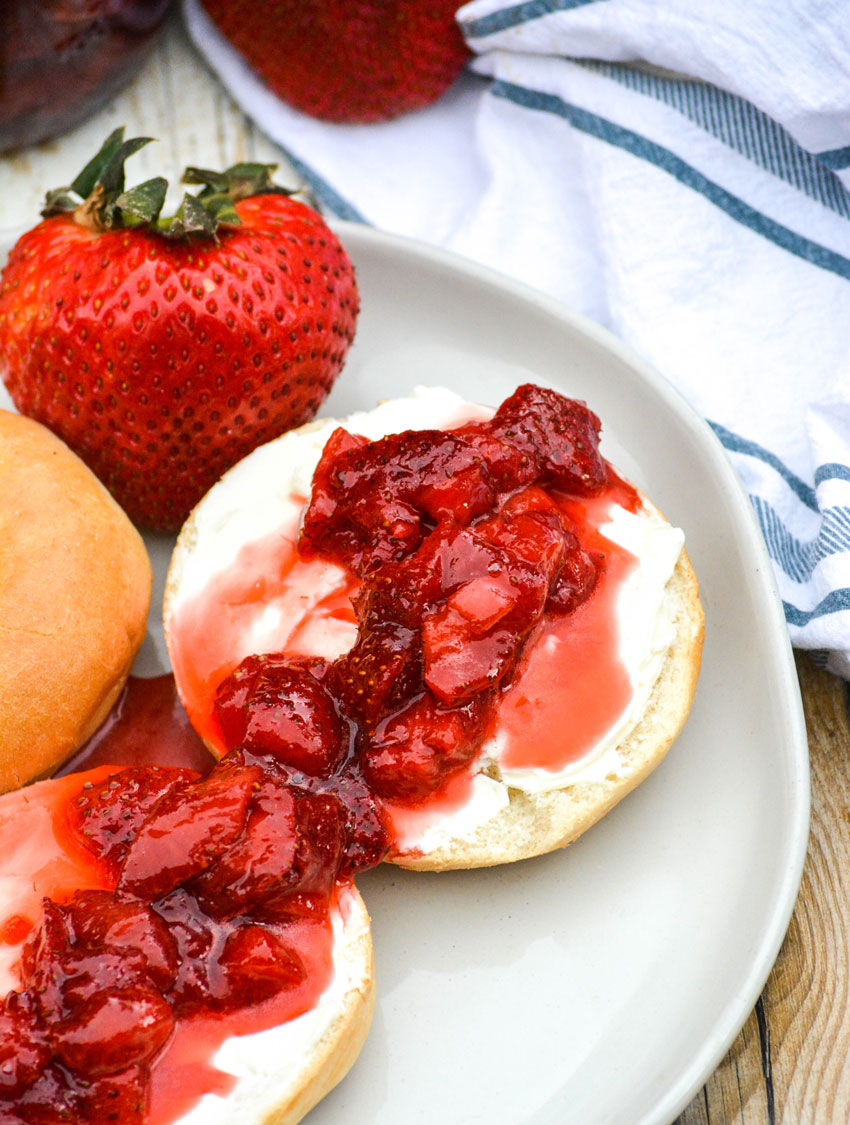 fresh strawberry sauce spread over cream cheese covered bagels on a gray plate